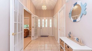 Un couloir doté d’un sol carrelé, de portes blanches et d’une console blanche sur laquelle sont posés des paniers.
