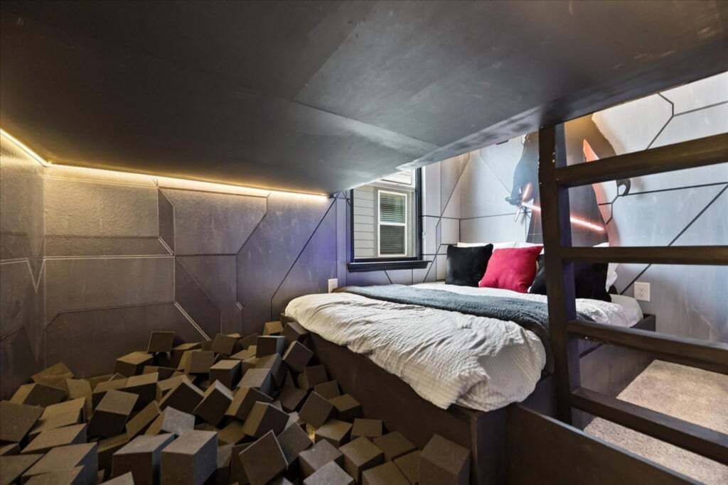 Une chambre à coucher moderne et compacte, dotée d’un lit superposé, d’un motif géométrique sur le mur et d’une fenêtre laissant entrer la lumière naturelle.
