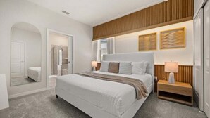 Un dormitorio moderno con una cama grande, mesitas de noche, un espejo y un panel de pared de madera.