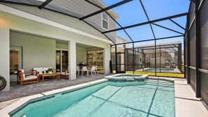 Una piscina con cerramiento de vidrio, mobiliario exterior y una zona de terraza.