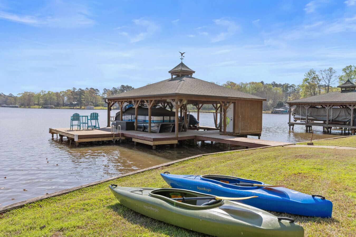 Une jetée au bord du lac, agrémentée d’un kiosque, de kayaks et d’un bateau.