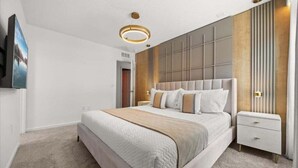 Een moderne slaapkamer met een groot bed, een nachtkastje, een aan de muur bevestigde televisie en een plafondlamp.