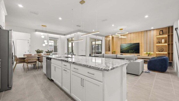Een moderne keuken met witte kastjes, een marmeren eiland en hanglampen.