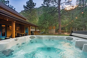 A hot tub in a backyard with a wooden deck and outdoor furniture. - Stargazer’s Sanctuary • Observatory Dome Retreat: Sauna & Hot Tub (Sedona)