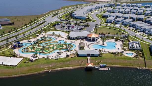 Vista aerea di un resort con un grande parco acquatico, diverse piscine e una zona residenziale con case a schiera.
