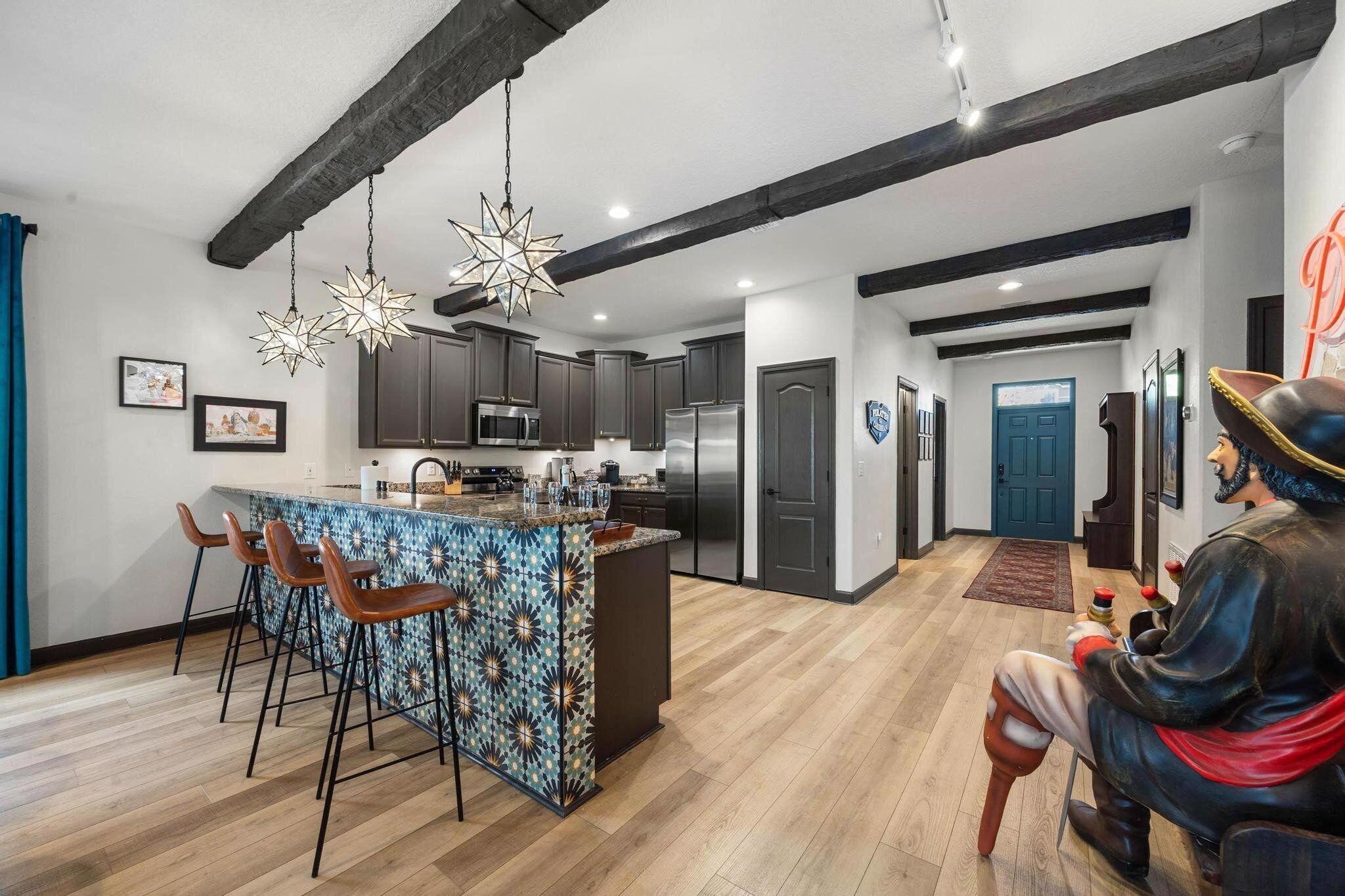 Una cucina moderna con mobili scuri, elettrodomestici in acciaio inossidabile e un'isola con motivo decorativo e sgabelli da bar.