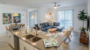 A modern kitchen with a central island, dining area, and a living space with a sofa and chairs. - Disney Getaway! Luxury Townhouse with Private Pool. Book Now! #CG902 (Orlando)