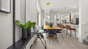 Un comedor moderno con una mesa larga, sillas e iluminación colgante.