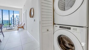 A laundry room with stacked washers and dryers, a view of the city through large windows, and a seating area with a view. - DTW Doral 2 BD Condo and Skyline Views (Miami)