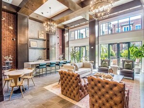A spacious living area with a kitchen, bar seating, and large windows offering views of the outdoors.