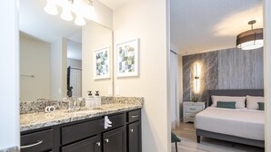 Una camera da letto moderna con un letto grande, un comodino e un bagno con un lavabo e uno specchio.