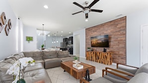 Ein modernes Wohnzimmer mit einem Ecksofa, einem Couchtisch und einem an einer Holzwand befestigten Fernseher.