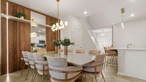 Una cocina moderna con una isla central, detalles de madera y una escalera que sube a otro nivel.