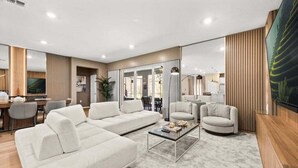 A modern living room with a sofa set, a coffee table, and a TV. - Last Minute Disney Getaway! Private Pool, Game Room & Themed Bedrooms. Book Now! #149063 (Orlando)