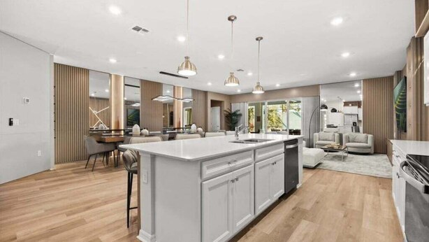 A modern kitchen with a large island, pendant lighting, and a dining area with a table and chairs. - Last Minute Disney Getaway! Private Pool, Game Room & Themed Bedrooms. Book Now! #149063 (Orlando)