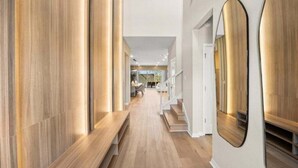 A modern hallway with wooden flooring, built-in benches, and a large mirror on the wall. - Last Minute Disney Getaway! Private Pool, Game Room & Themed Bedrooms. Book Now! #149063 (Orlando)
