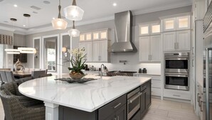 A modern kitchen with a large island, stainless steel appliances, and pendant lighting. - Last Minute Disney Getaway! Private Pool & Home Theater. Book Now! #158253 (Orlando)