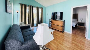 A living room with a sofa, a TV, a lamp, and a wooden cabinet. - Top-Floor River Oaks Escape  2BR, 2BA (Myrtle Beach)