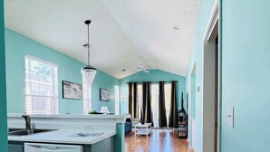 A spacious kitchen with a dishwasher, a dining area with a chandelier, and a hallway with a ceiling fan. - Top-Floor River Oaks Escape  2BR, 2BA (Myrtle Beach)