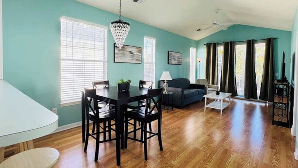 A spacious living room with a dining area, wooden flooring, and teal walls. - Top-Floor River Oaks Escape  2BR, 2BA (Myrtle Beach)