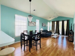 A spacious living room with a dining area, wooden flooring, and teal walls. - Top-Floor River Oaks Escape  2BR, 2BA (Myrtle Beach)