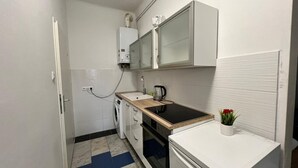 A compact kitchen with a washing machine, a stove, and a microwave. - Cozy Room in Apartment, Prime Locatio (Wien)