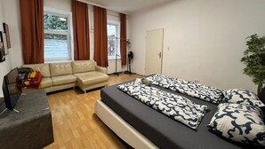 A room with a bed, a sofa, a TV, and a window with curtains. - Cozy Room in Apartment, Prime Locatio (Wien)