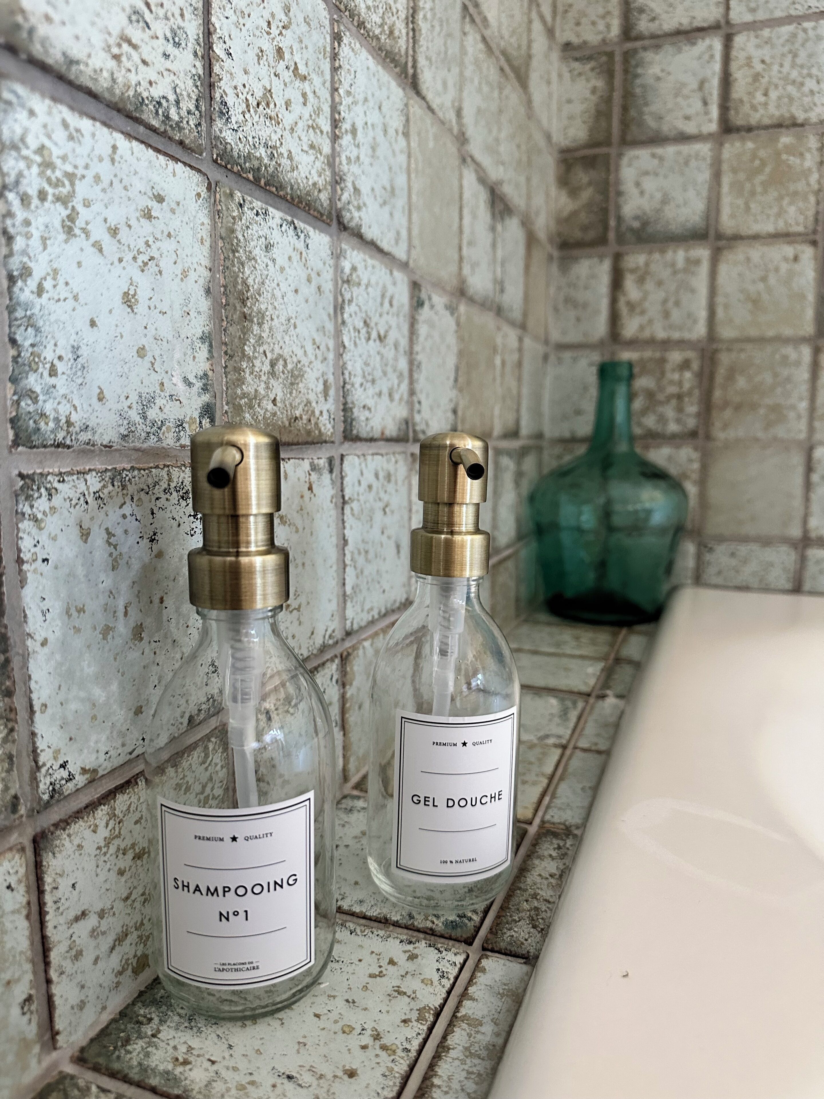 Two glass bottles with labels on a tiled surface.