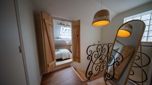 A bedroom with a bed, a window, a mirror, and a hanging light fixture. - L'écrin du Sancy, a gentle cocoon just a stone's throw from La Bourboule town center. (La Bourboule)
