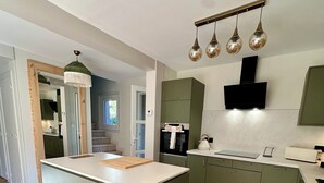 A modern kitchen with a central island, green cabinets, and a built-in oven. - L'écrin du Sancy, a gentle cocoon just a stone's throw from La Bourboule town center. (La Bourboule)