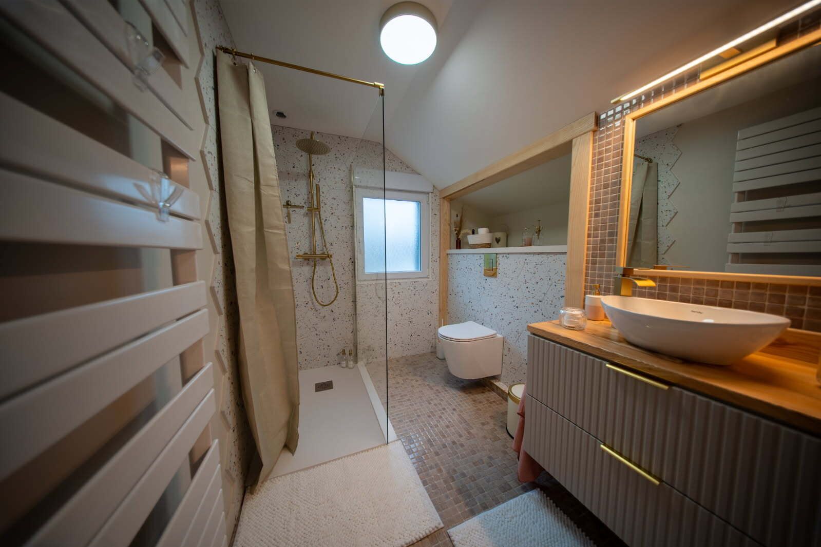 Un bagno moderno con cabina doccia, un water e un lavabo con uno specchio grande.