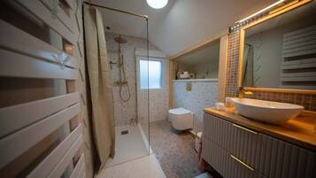 Un bagno moderno con cabina doccia, un water e un lavabo con uno specchio grande.