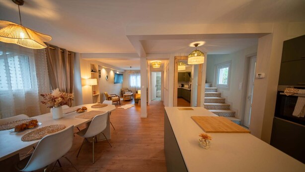 A spacious kitchen with a central island, a dining area with chairs and a table, and a staircase leading to an upper floor. - L'écrin du Sancy, a gentle cocoon just a stone's throw from La Bourboule town center. (La Bourboule)