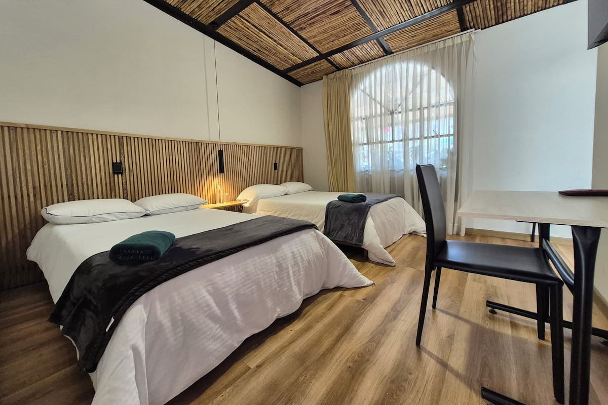 A hotel room with two beds, a desk, and a chair.