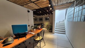 A modern office space with a wooden desk, a blue chair, a laptop, a plant, and a staircase leading to another level. - Pepe's House Usaquén Bogotá -Small Hotel (Bogotá)