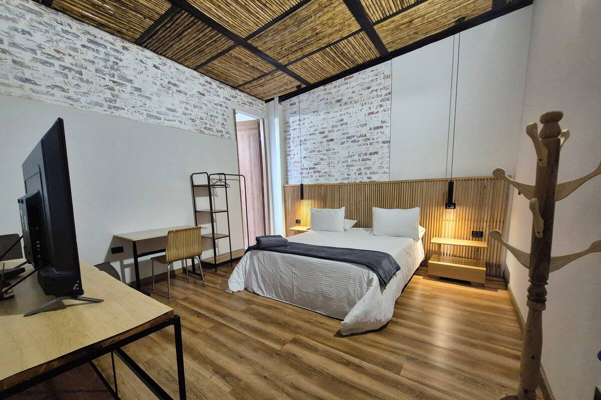 A hotel room with a bed, desk, chair, and a television.