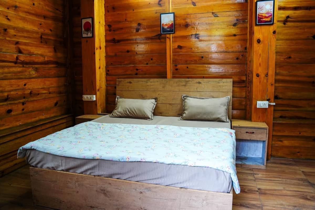 A wooden cabin room with a bed, two nightstands, and a wall with framed pictures.