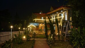 A two-story house with a wooden exterior, a red roof, and a brick pathway leading to the entrance. - 7 Lake Stays Sattal (India)