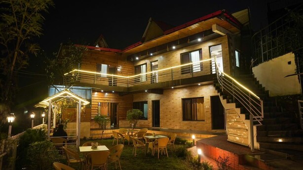 A two-story building with a wooden exterior, a covered outdoor seating area, and a staircase leading to the upper floor. - 7 Lake Stays Sattal (India)