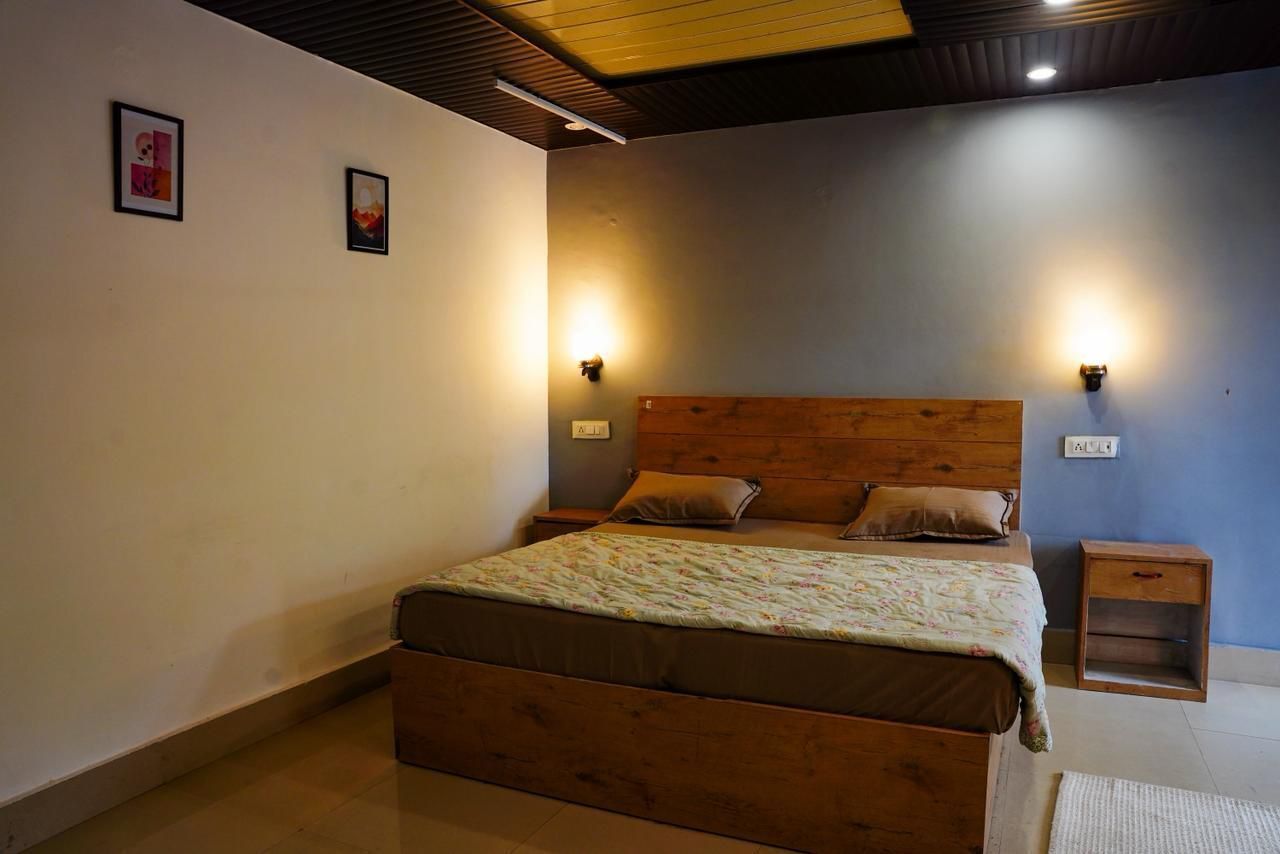 A bedroom with a wooden bed, two bedside tables, and wall-mounted lights.