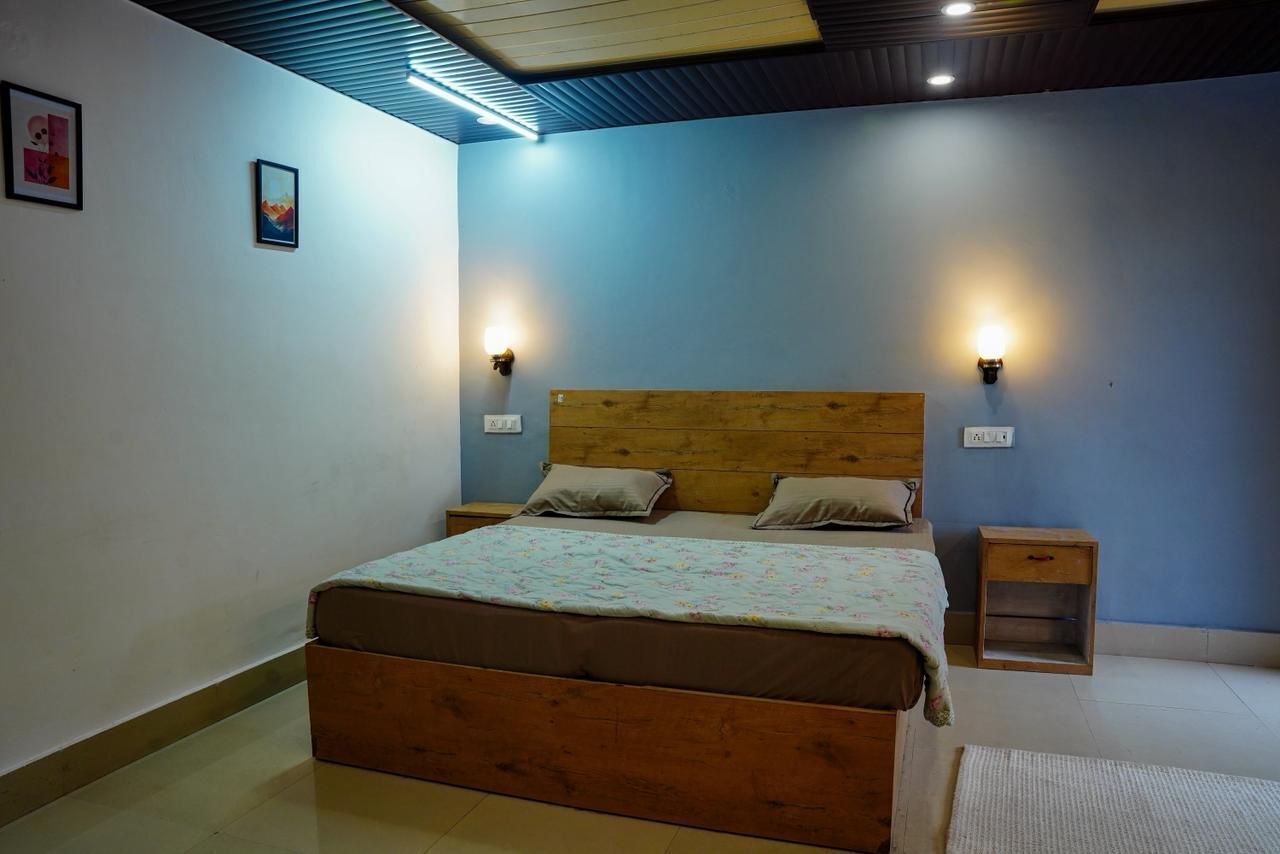 Un dormitorio con una cama de madera, dos mesitas de noche y luces fijadas en la pared.