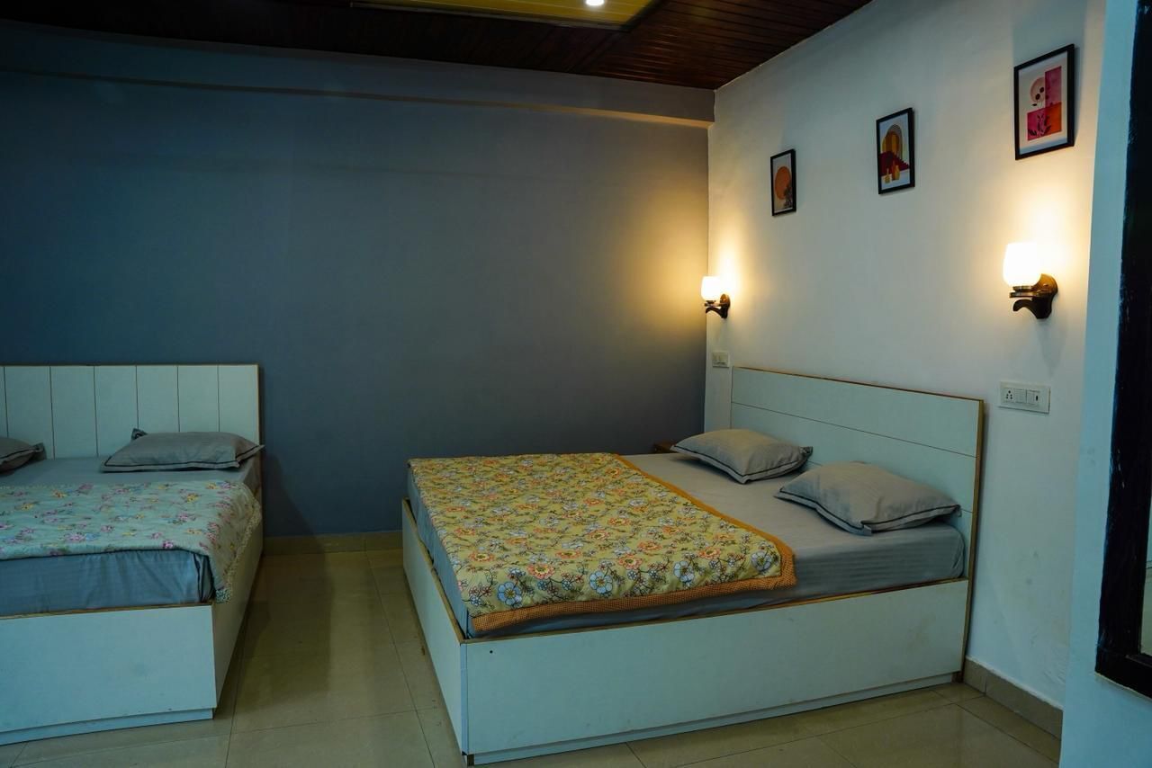 A bedroom with two beds, each with a headboard and bedside lamps.