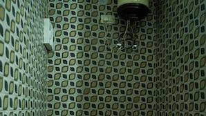 A bathroom with a toilet, a water heater, and a patterned wall. - 7 Lake Stays Sattal (India)