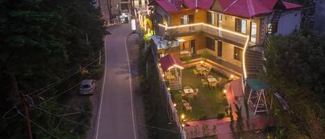 A two-story building with a red roof, a balcony, and outdoor seating.