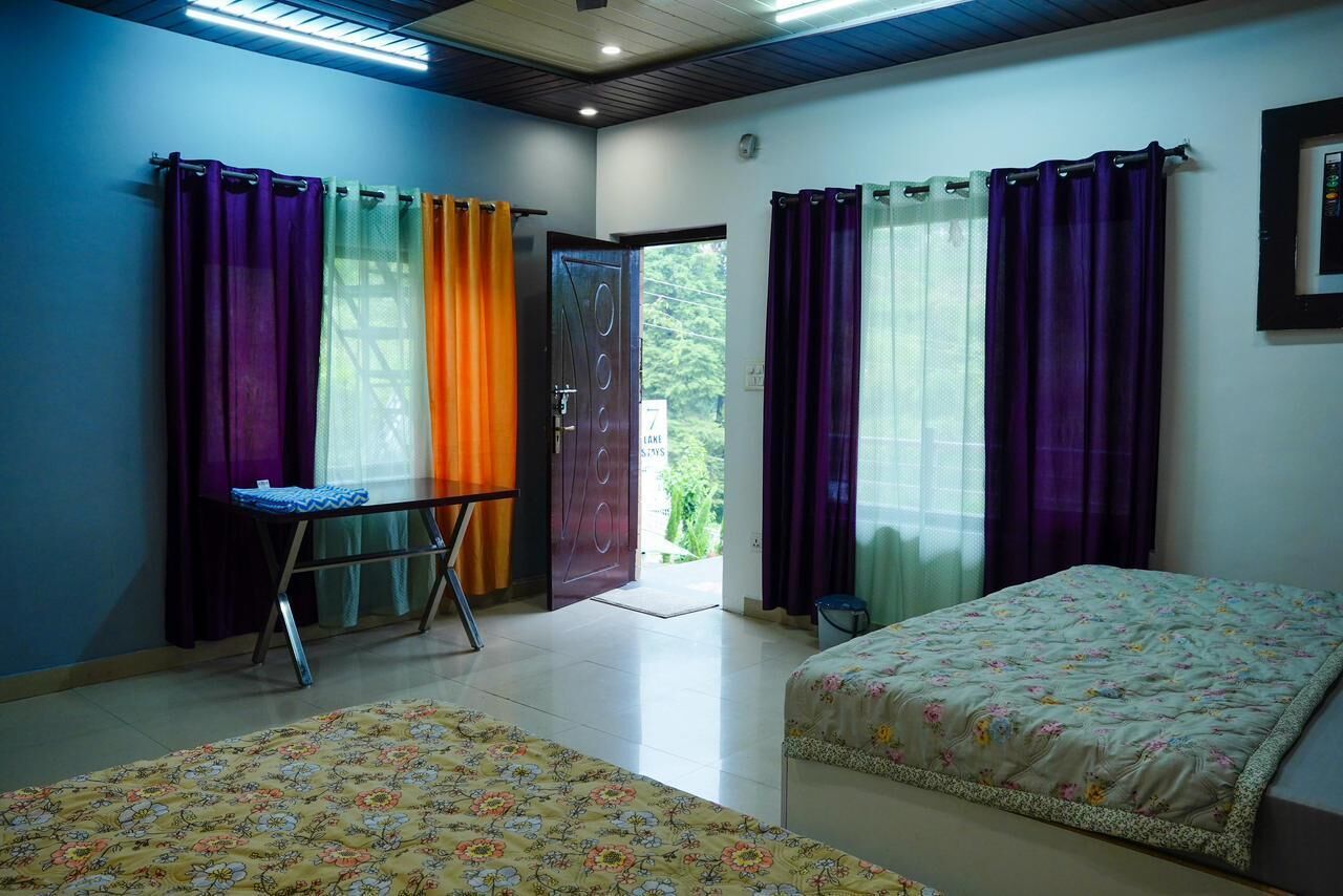 Une chambre avec deux lits, un bureau et une porte donnant sur l’extérieur.