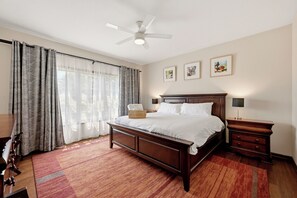 A bedroom with a bed, a nightstand, a lamp, a ceiling fan, and a window with curtains.