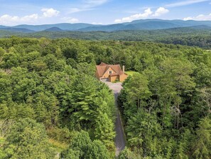 A house surrounded by dense forest with a clear sky.