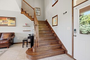 A wooden staircase with a handrail, a brown leather sofa, a small table, and a door with a window.