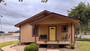 Ein eingeschossiges Haus mit Veranda, einer Tür und zwei Fenstern.