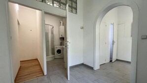 Ett tvättrum med tvättmaskin och torktumlare, en trädörr och ett klinkergolv.